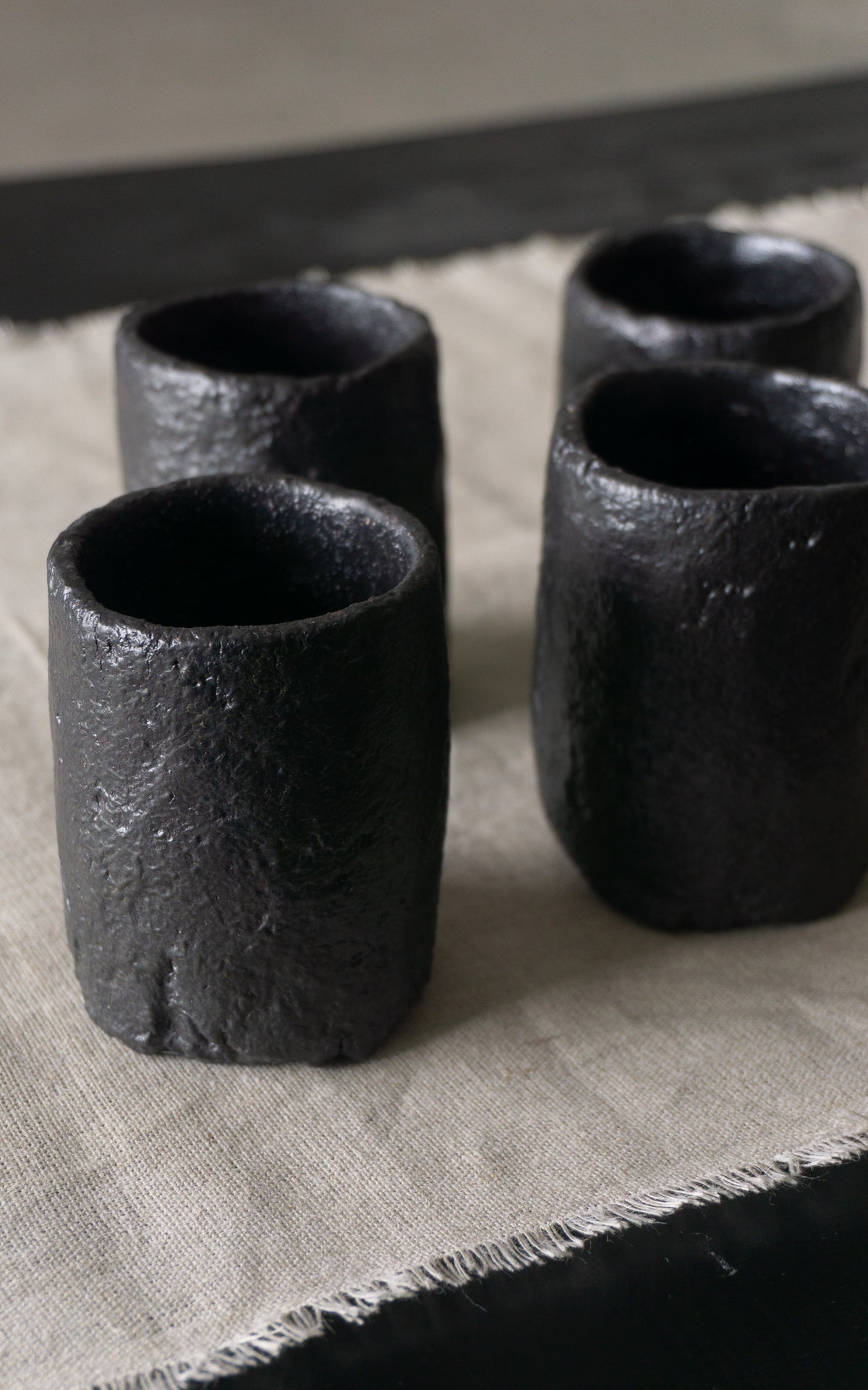 Set of four black ceramic cups on a textured surface
