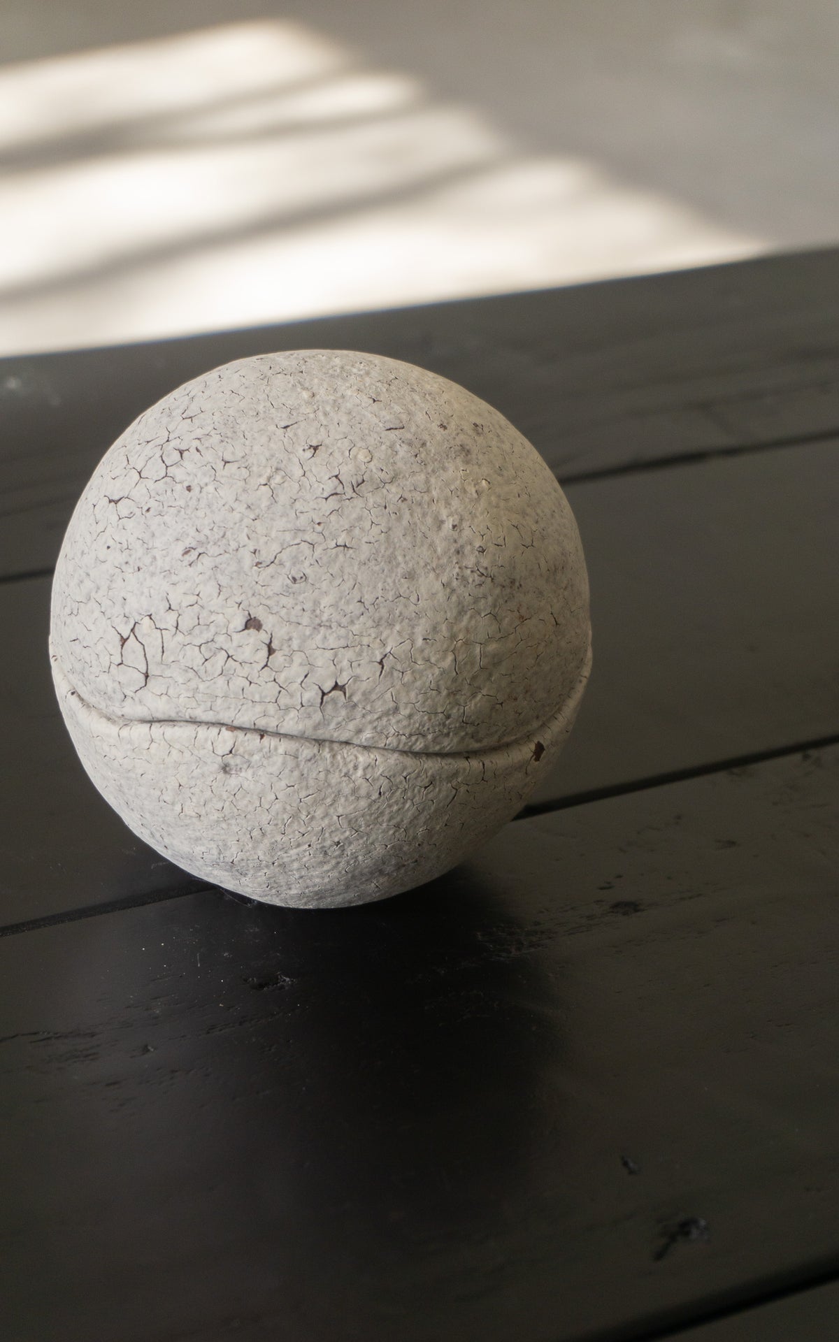 White ceramic spherical bowl on a black wooden table.