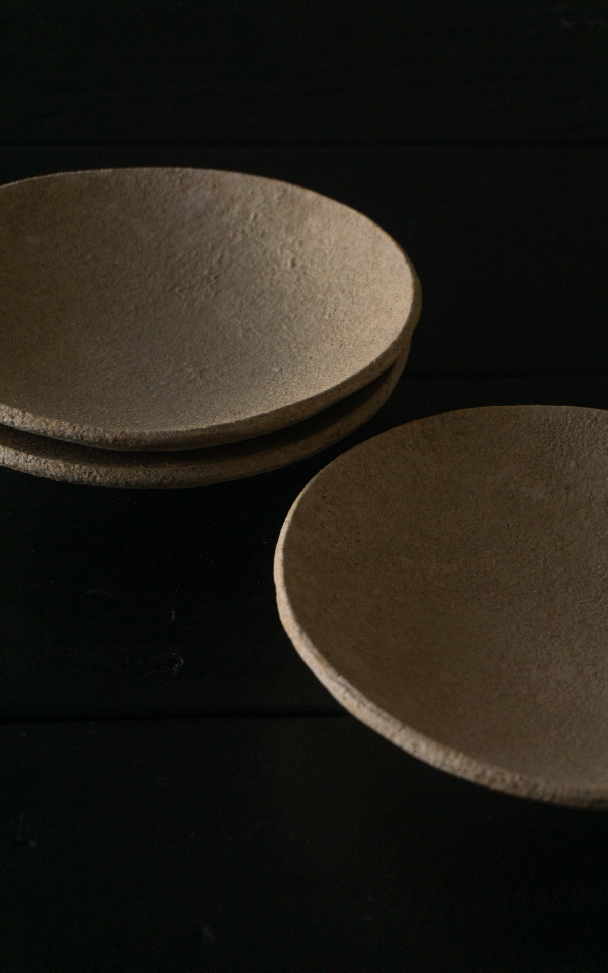 Set of round, beige-colored ceramic plates on a black background