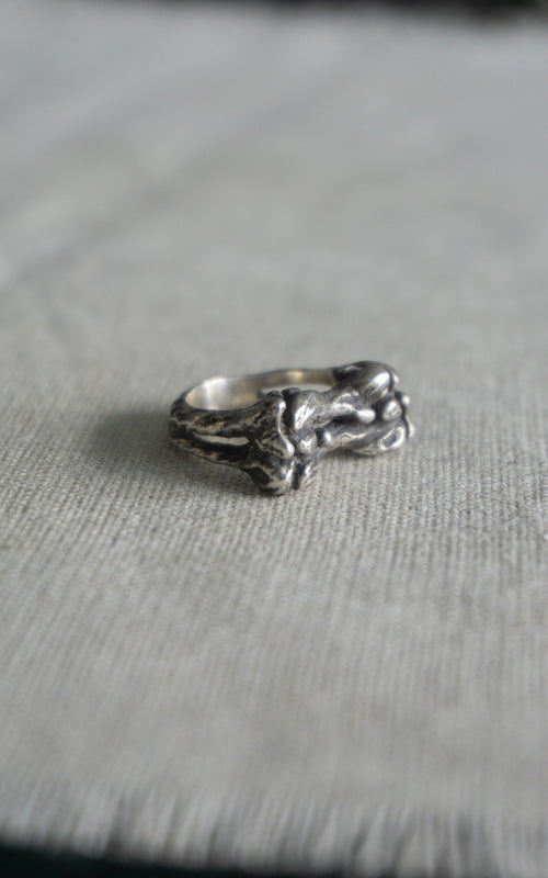 Silver patina bone ring with a unique design on a gray surface