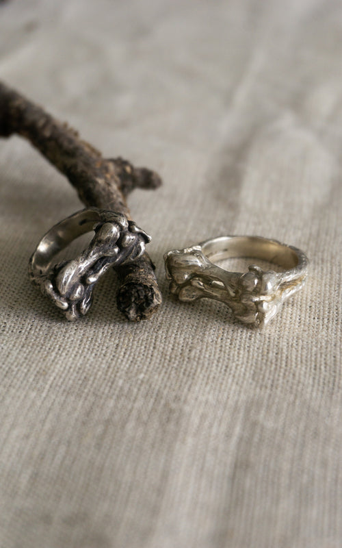 Two silver bone rings on a textured surface